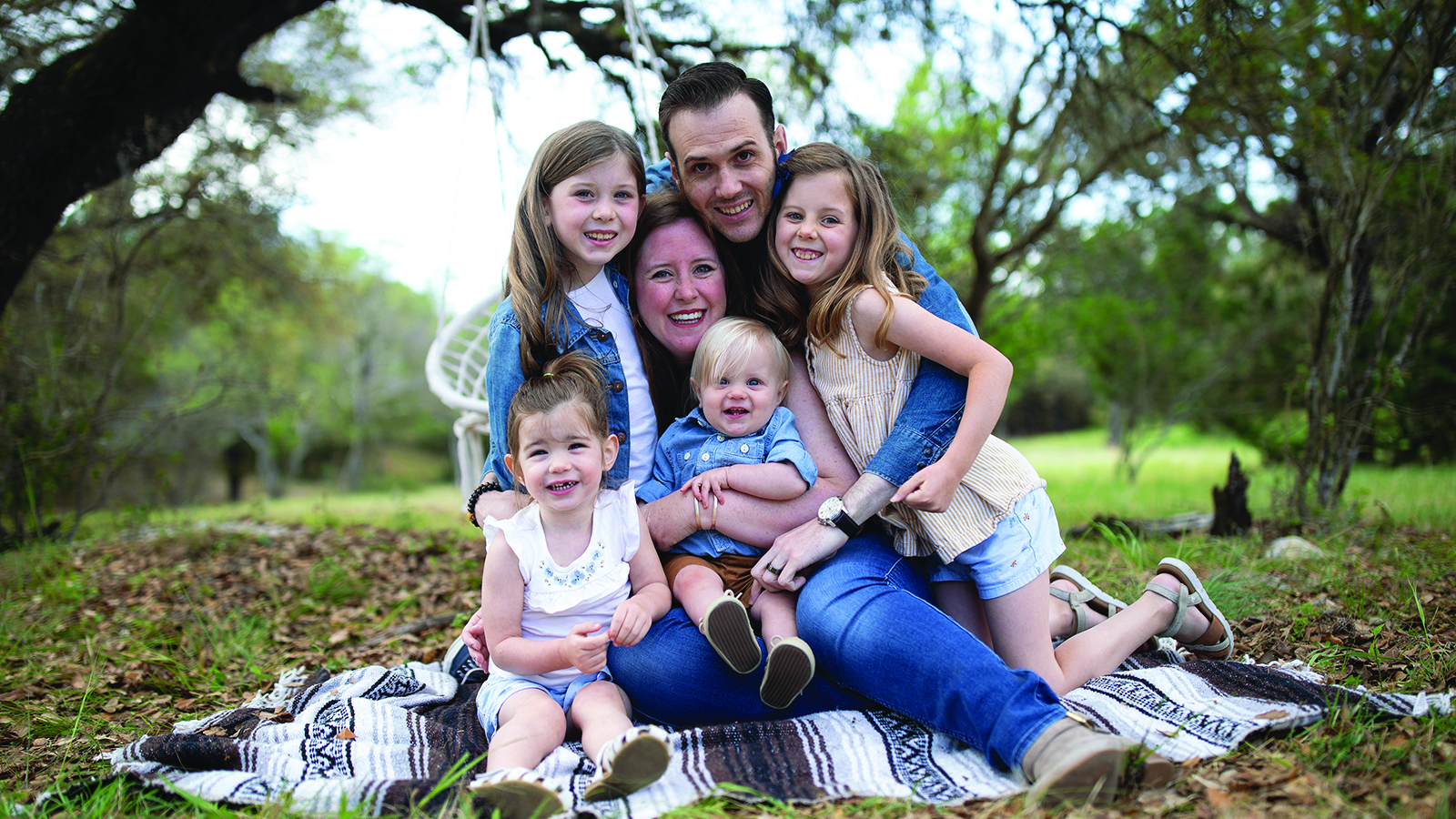 Service member hugs his family on blanket.