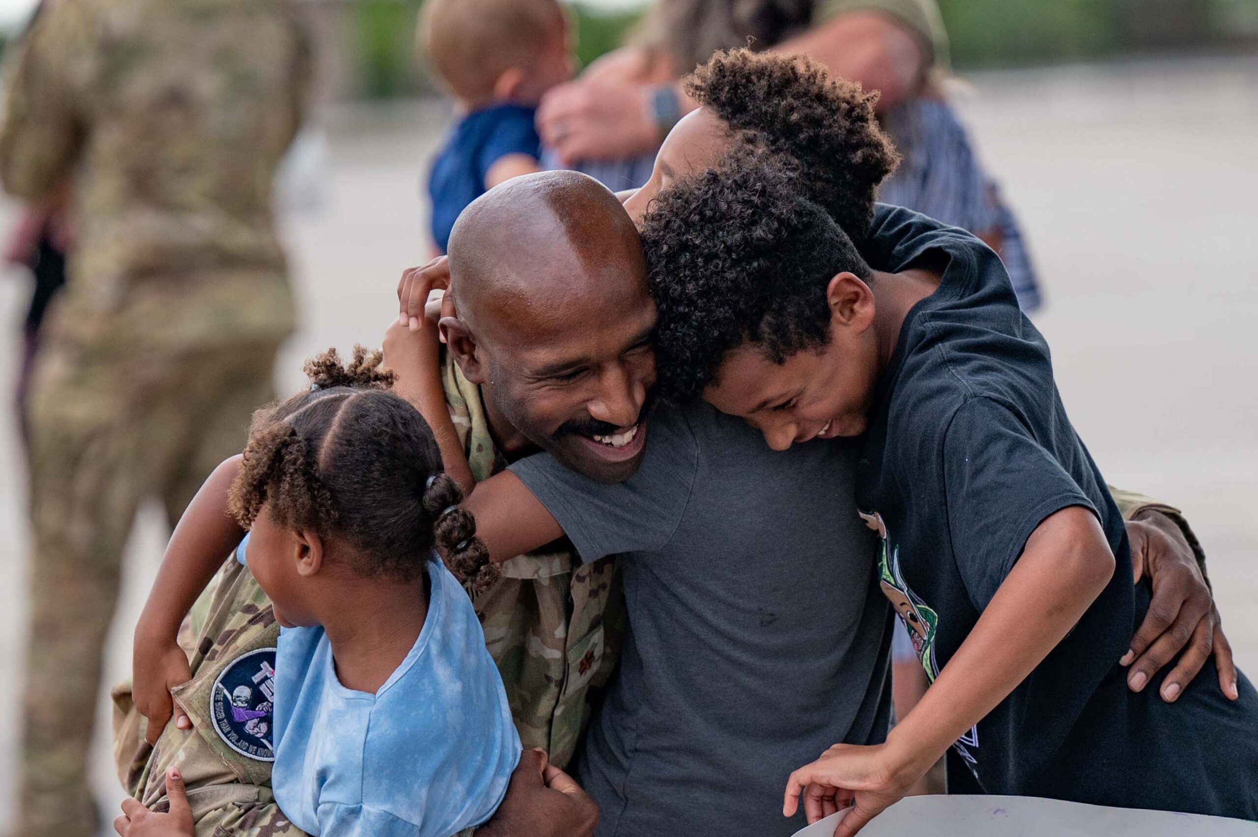 military dad hugging children