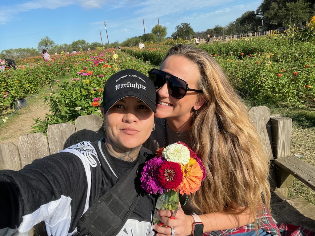 two women hugging and holding flowers