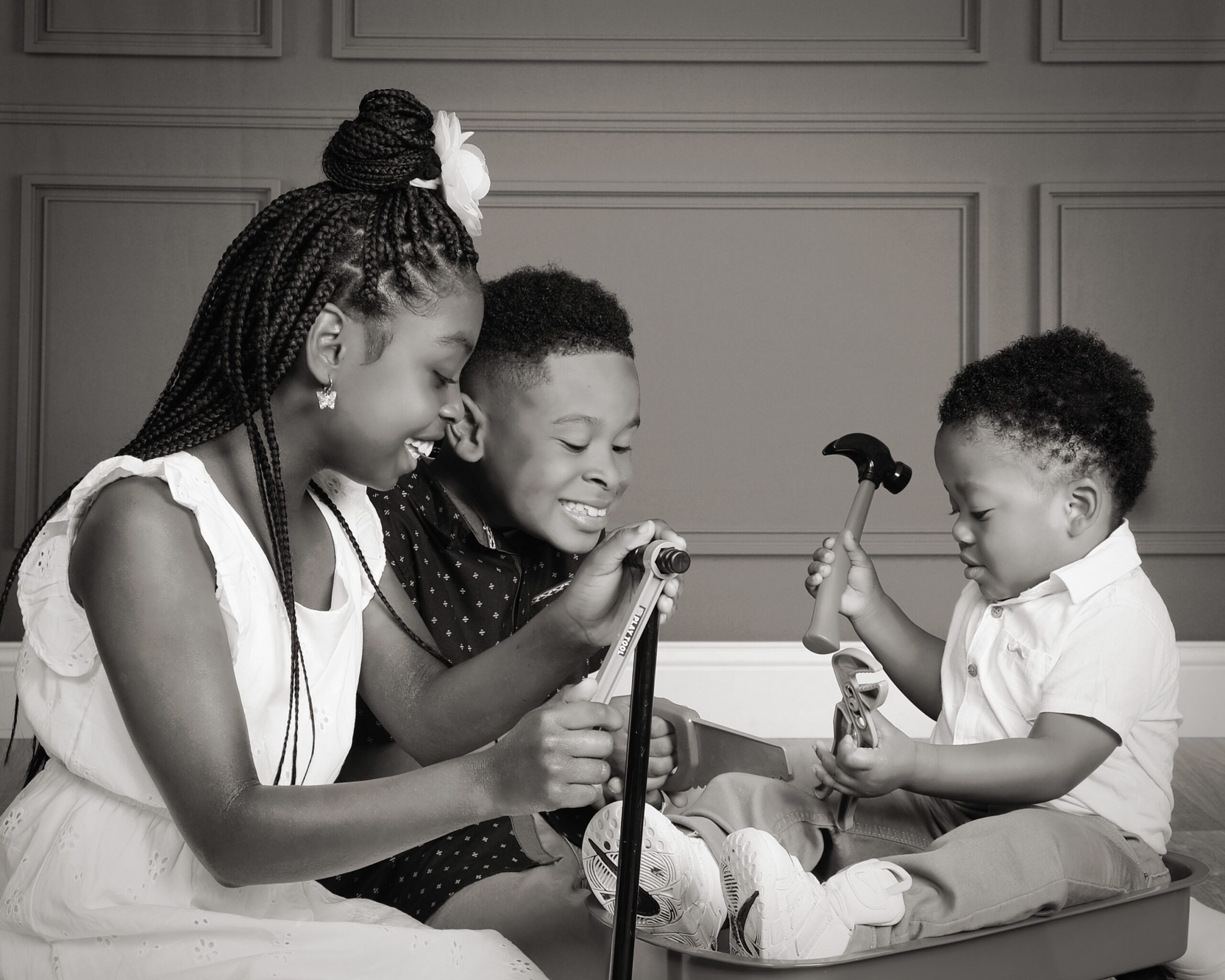 three children playing with tools for family photo